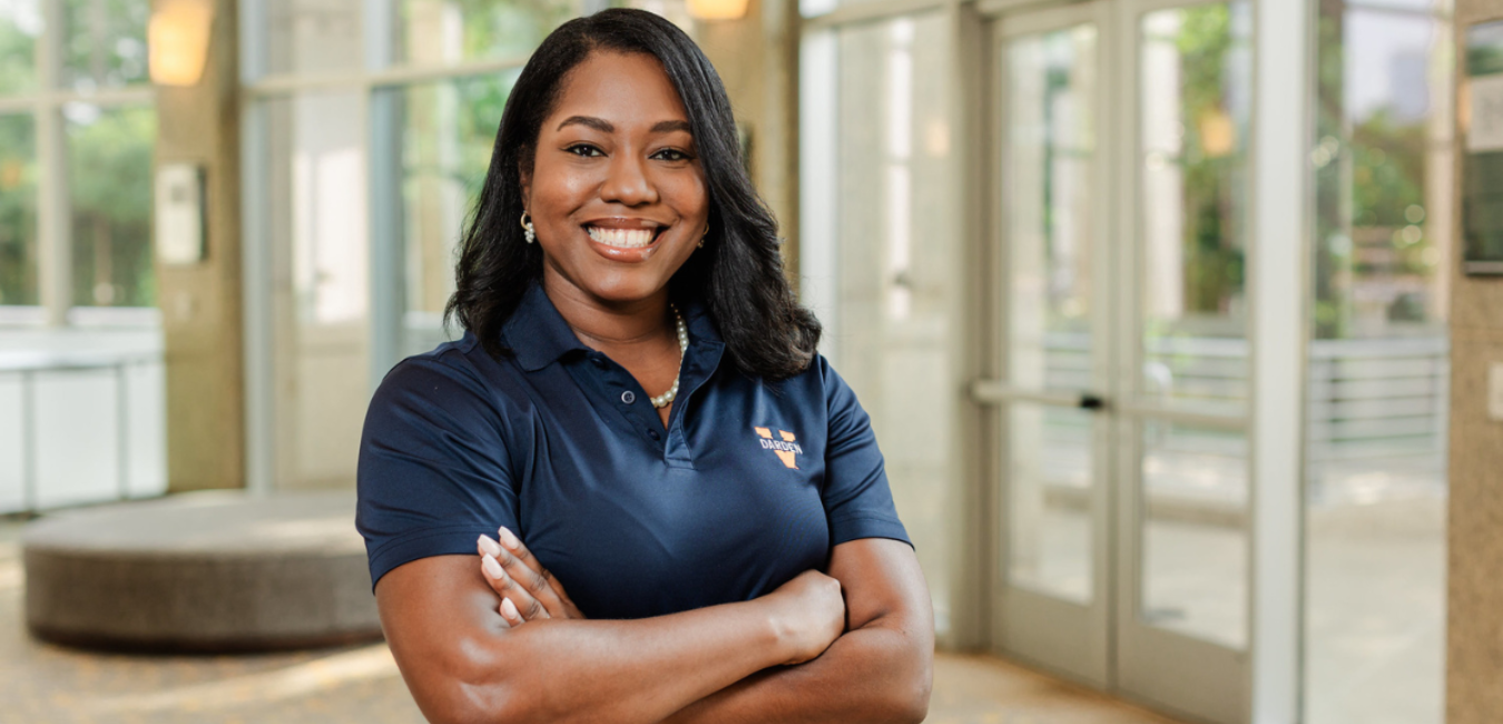 Picture of Forte Foundation member Black woman with arms crossed inside of business school building during daylight