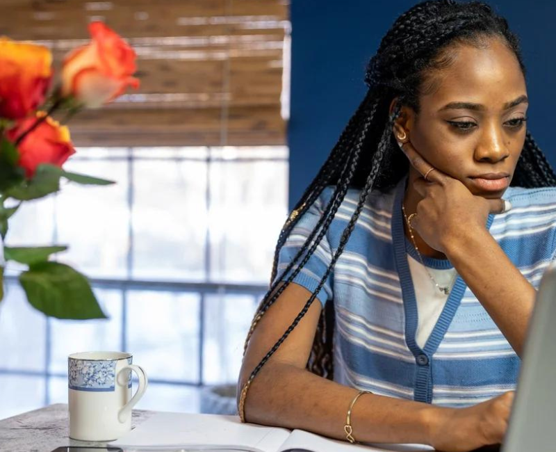 Black Woman at desk in front of computer contemplating career transition in front of computer