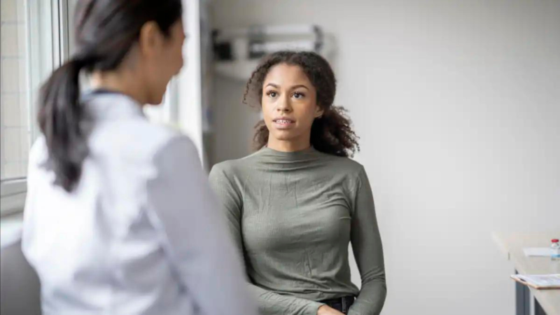Black Woman facing Doctor discussing FMLA