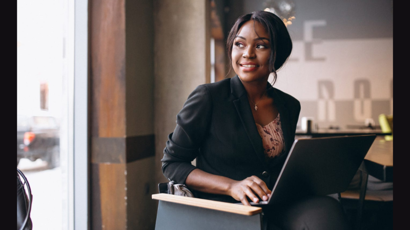 Career Pivots Black woman professional seated looking out of window with laptop