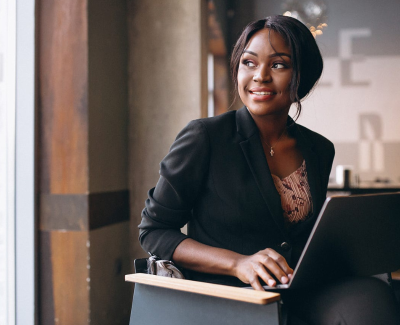 Career Pivots Black woman professional seated looking out of window with laptop