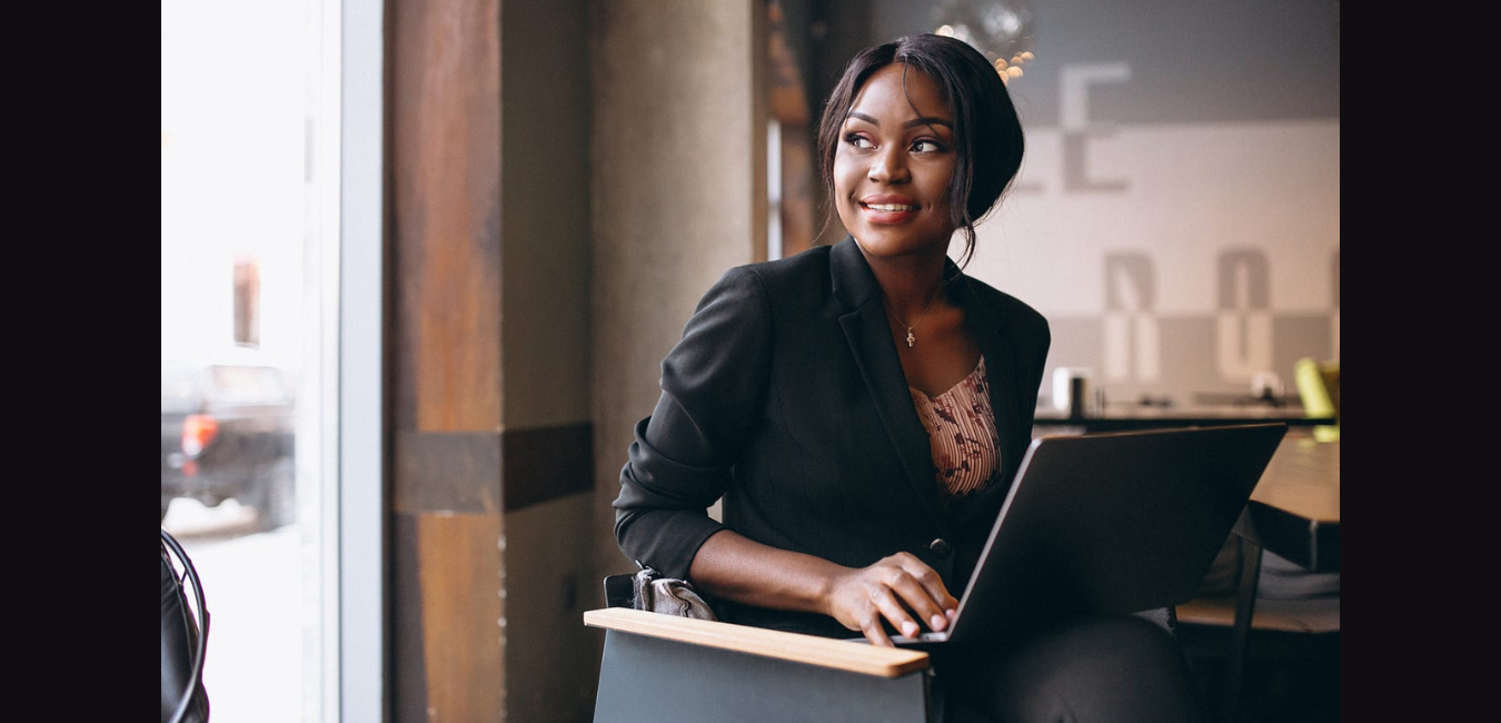 Career Pivots Black woman professional seated looking out of window with laptop