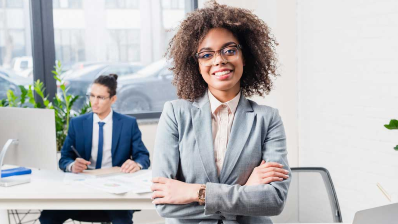 Maximize Your Career Success Black woman in office with natural hair and classes in suit with arms folded