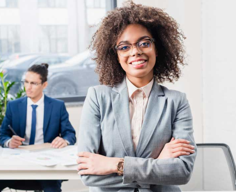 Maximize Your Career Success Black woman in office with natural hair and classes in suit with arms folded