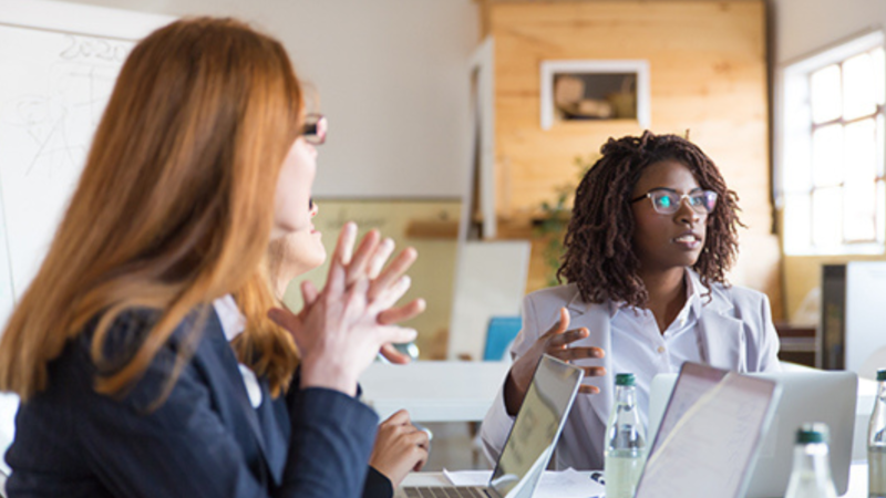 Defend Yourself black woman with natural hair in meeting with two white women who are blurred