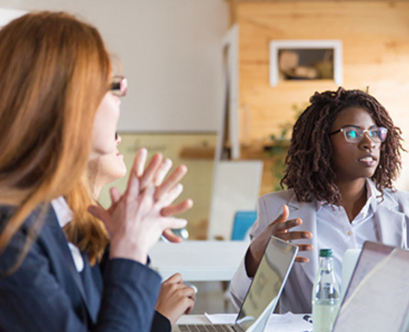 Defend Yourself black woman with natural hair in meeting with two white women who are blurred