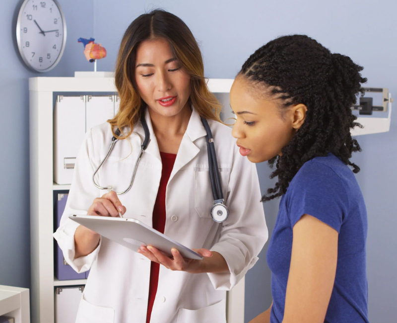 Black woman with doctor looking at paperwork. Need a Break? Here's Exactly How to Take FMLA